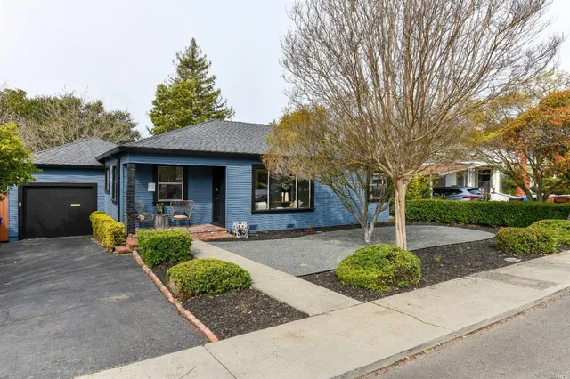 a front view of a house with garden and trees