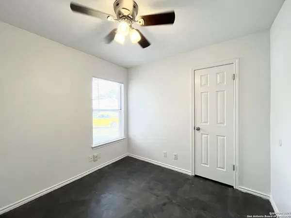 an empty room with windows and fan