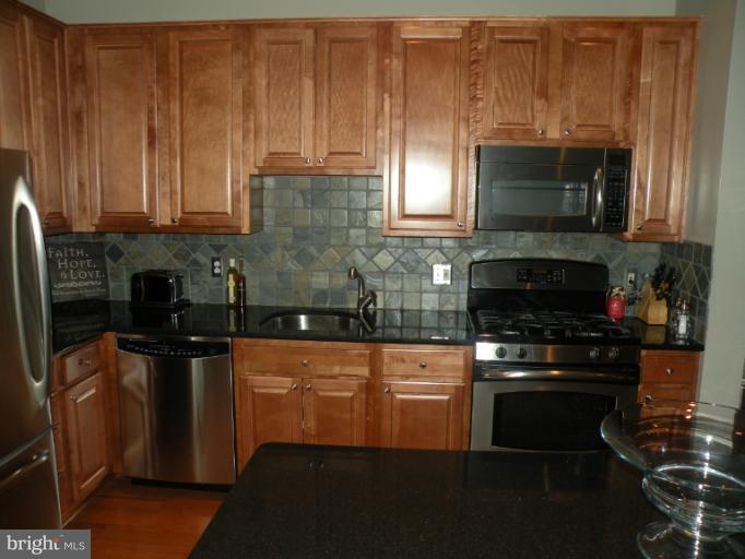 12000 Market Street, Unit 438 Reston, VA 20190 - Photo 2 of 13 a kitchen with granite countertop a stove and a microwave