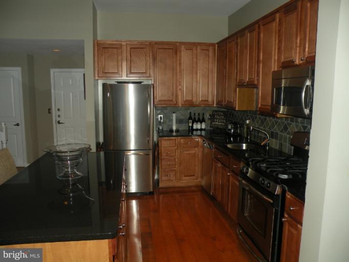 12000 Market Street, Unit 438 Reston, VA 20190 - Photo 4 of 13 a kitchen with a black stainless steel appliances a refrigerator and a stove top oven