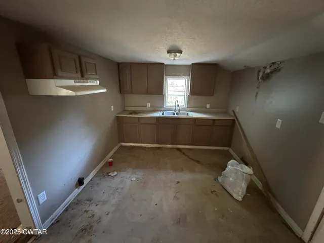 a room with granite countertop a sink and cabinets