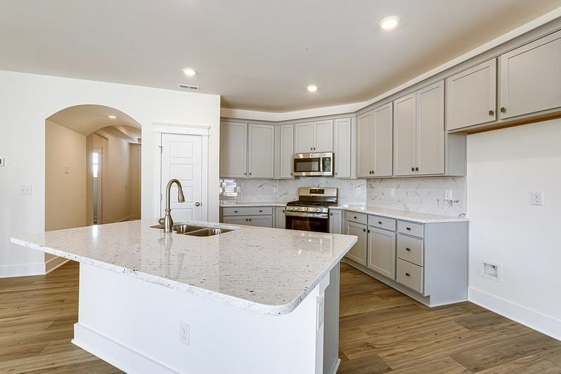 1000 Heartstone Way Durham, NC 27713 - Photo 5 of 35 a kitchen with kitchen island granite countertop a sink a stove and cabinets
