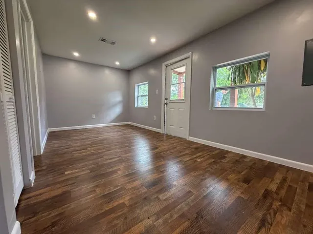an empty room with wooden floor and windows