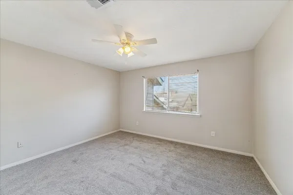 an empty room with a window and a fan