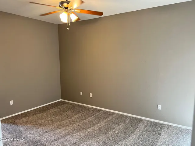 a view of an empty room with window and chandelier fan