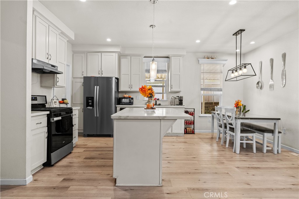 7101 Rosecrans Avenue, Unit 137 Paramount, CA 90723 - Photo 2 of 30 a kitchen with stainless steel appliances kitchen island granite countertop a refrigerator a stove a sink and a dining table with wooden floor