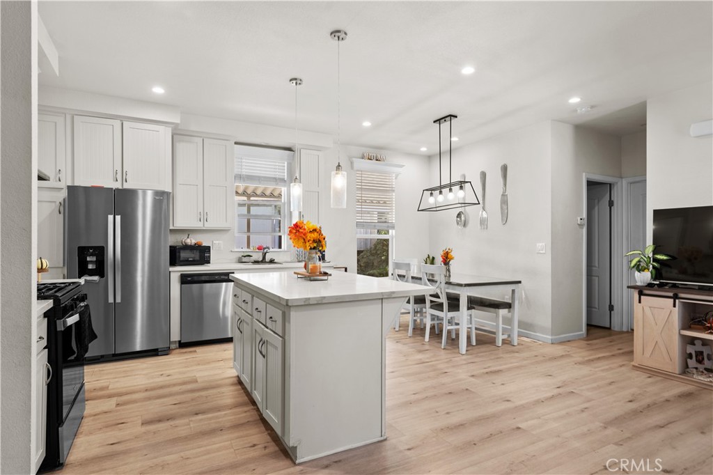 7101 Rosecrans Avenue, Unit 137 Paramount, CA 90723 - Photo 6 of 30 a kitchen with stainless steel appliances a stove top oven a refrigerator a kitchen island and chairs with wooden floor