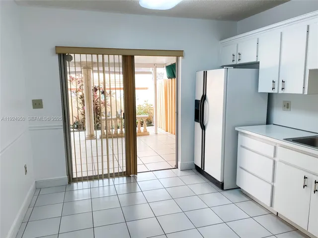 a kitchen with white cabinets a refrigerator and a sink