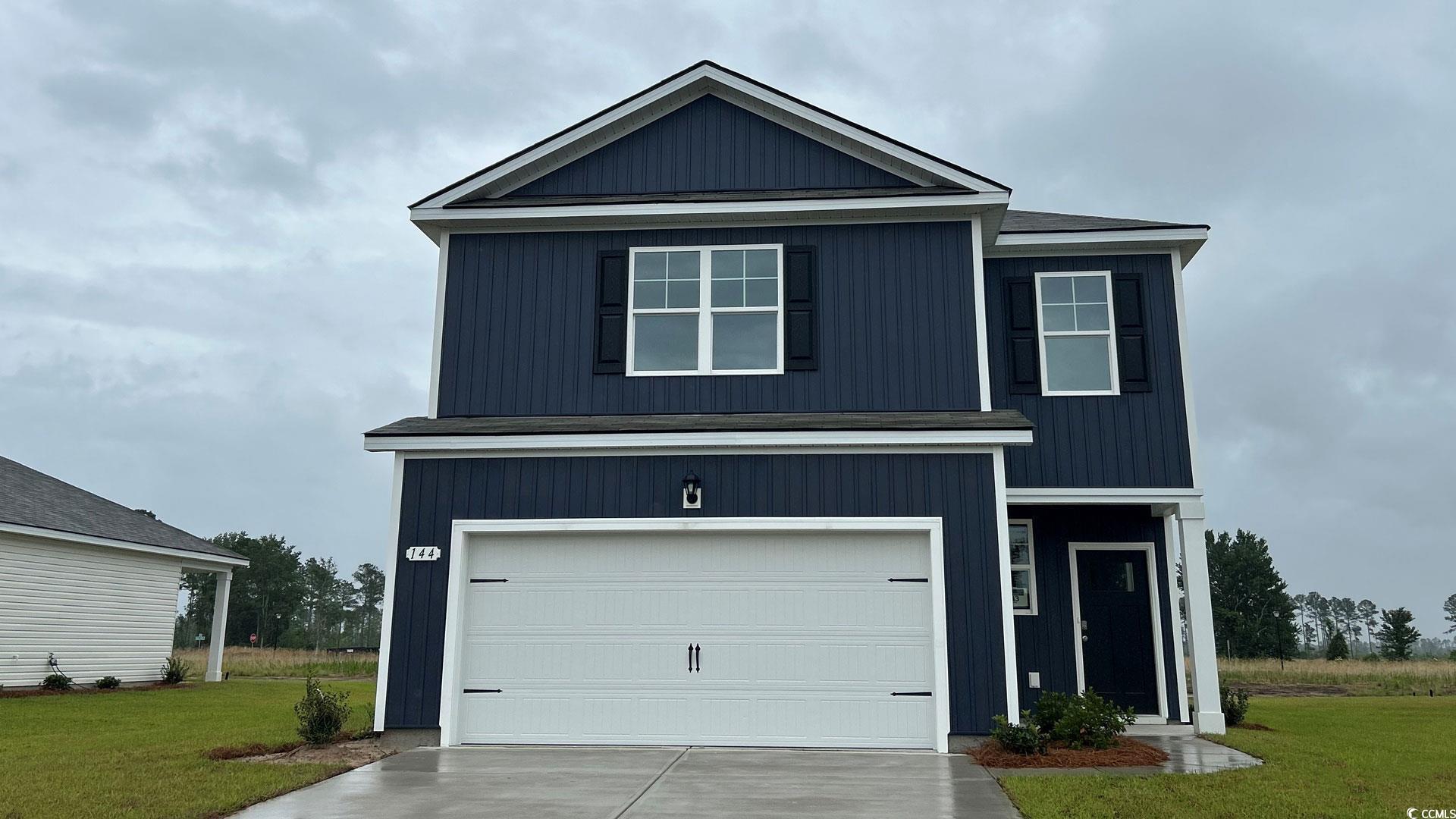 View of front of house with a front lawn, driveway, and an attached garage