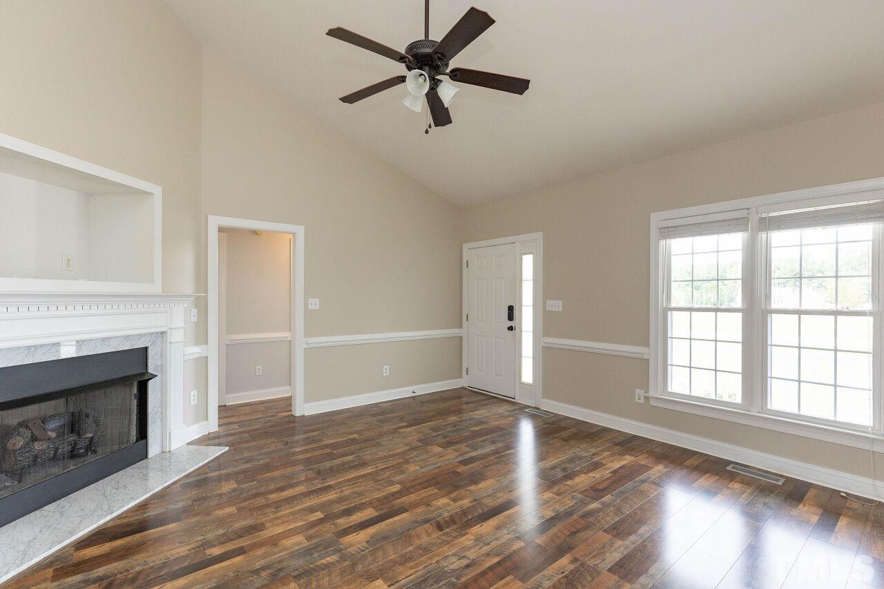 6573 Madison Road Bailey, NC 27807 - Photo 6 of 31 an empty room with wooden floor a ceiling fan and a fireplace
