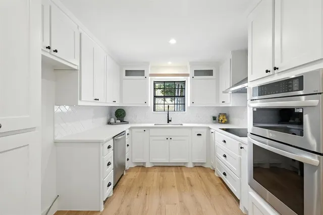 a kitchen with white cabinets appliances and sink