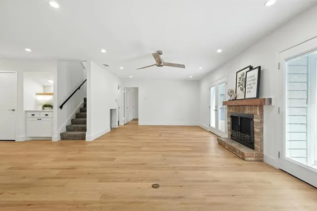 a view of an empty room with wooden floor fireplace and windows