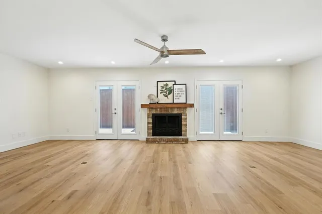 an empty room with wooden floor fireplace and windows