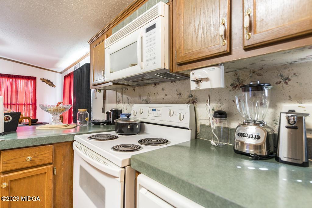 1592 Tribble Road Fort Valley, GA 31030 - Photo 22 of 30 a kitchen with a sink a stove and white cabinets