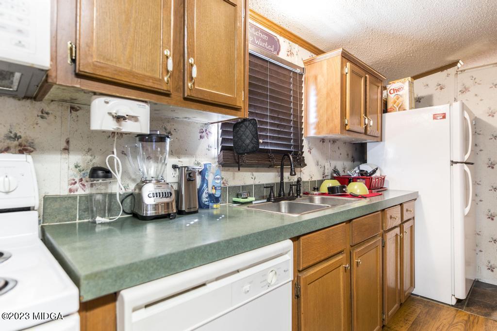 1592 Tribble Road Fort Valley, GA 31030 - Photo 23 of 30 a kitchen with stainless steel appliances granite countertop a sink a refrigerator and a white cabinets
