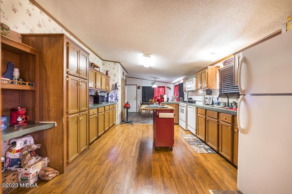 1592 Tribble Road Fort Valley, GA 31030 - Photo 25 of 30 a kitchen with stainless steel appliances granite countertop a refrigerator a stove top oven and a wooden floors