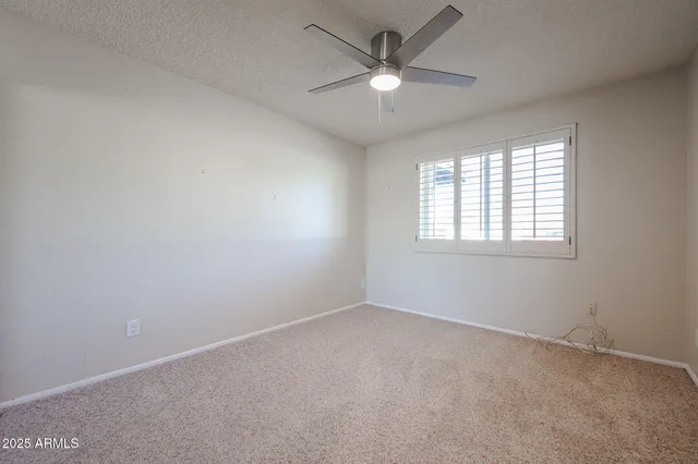 an empty room with windows and ceiling fan