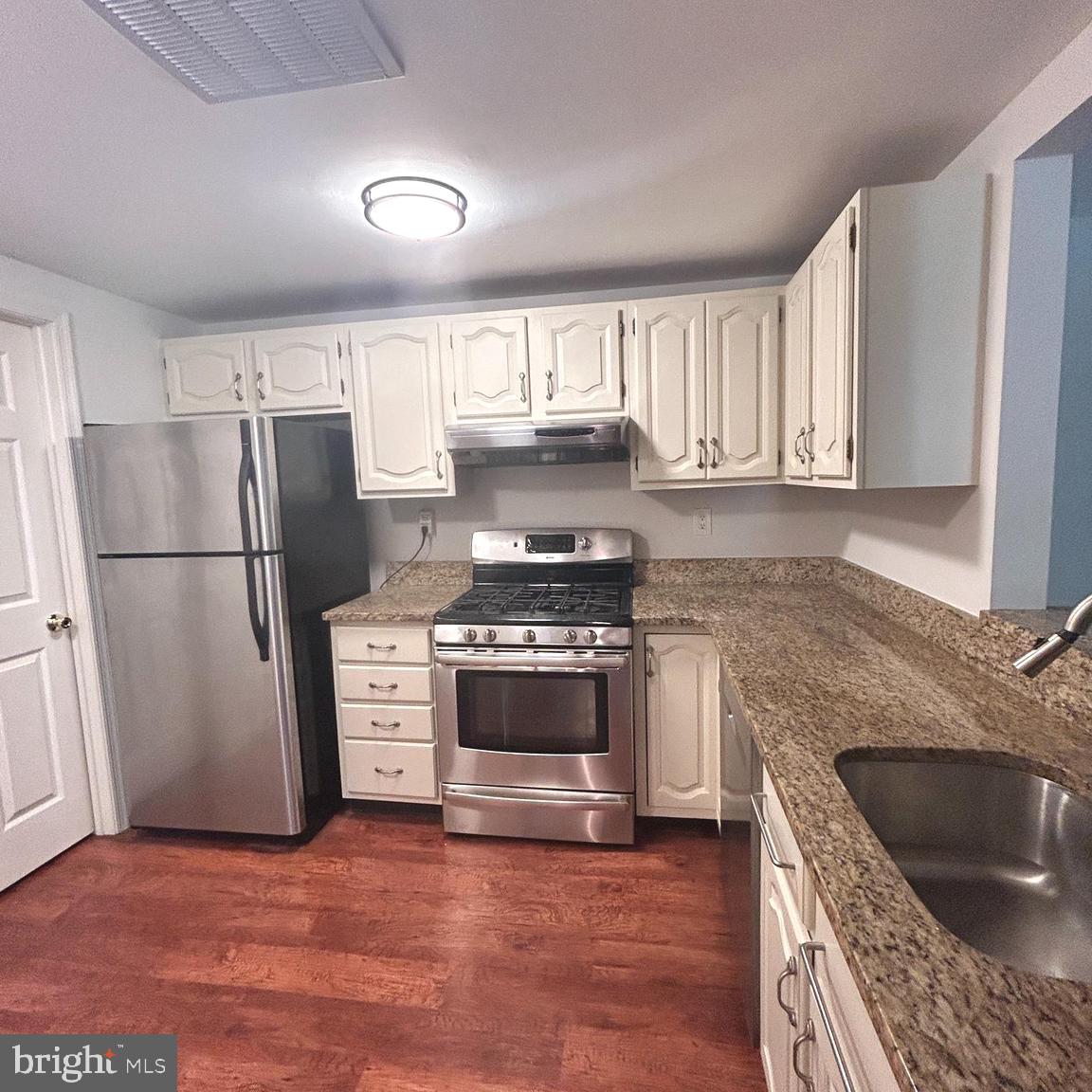 a kitchen with granite countertop a refrigerator stove and sink