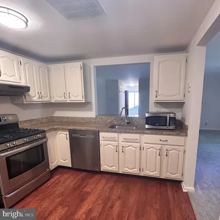 a kitchen with stainless steel appliances granite countertop a stove a sink and white cabinets