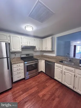 a kitchen with granite countertop wooden floors and white stainless steel appliances