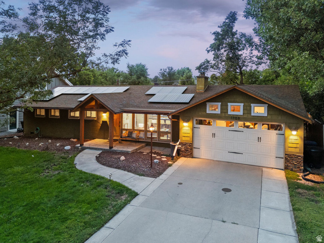 1709 Meadowmoor Road Holladay, UT 84117 - Photo 2 of 32 Gable roofline with solar panels, covered front entry, attached garage with decorative hardware, stone accents on exterior walls, and a concrete driveway