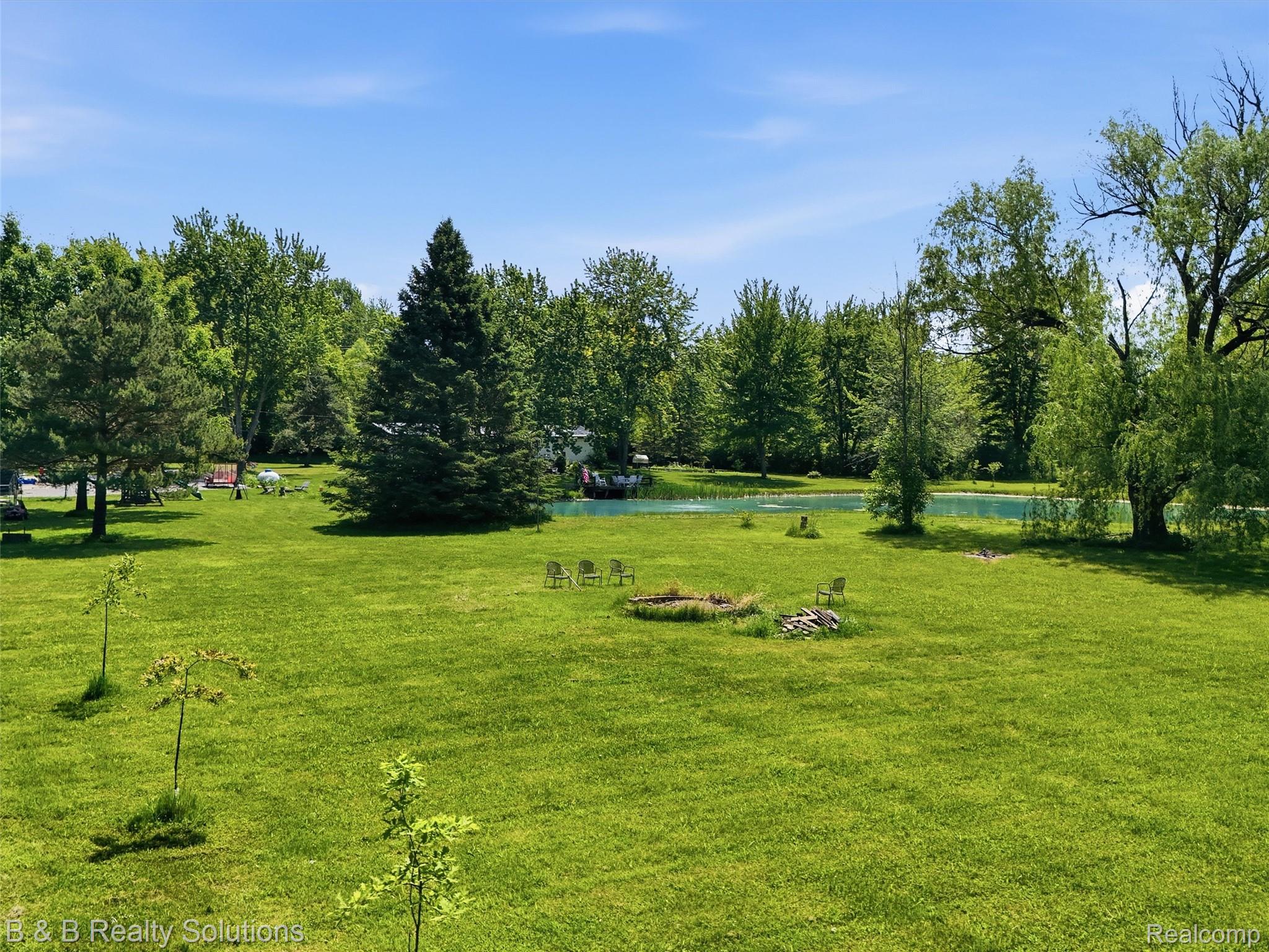 60455 Bates Road New Haven, MI 48048 - Photo 10 of 58 Expansive green lawn with mature trees and a tranquil pond