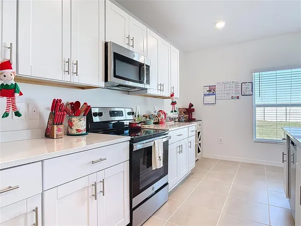 a kitchen with stainless steel appliances granite countertop white cabinets sink and window