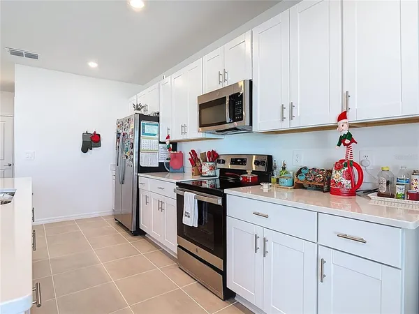 a kitchen with stainless steel appliances granite countertop white cabinets sink and a refrigerator