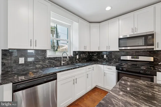a kitchen with stainless steel appliances granite countertop a stove a sink and a microwave