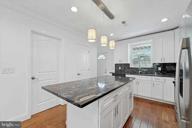 a kitchen with a sink dishwasher a stove and white cabinets with wooden floor