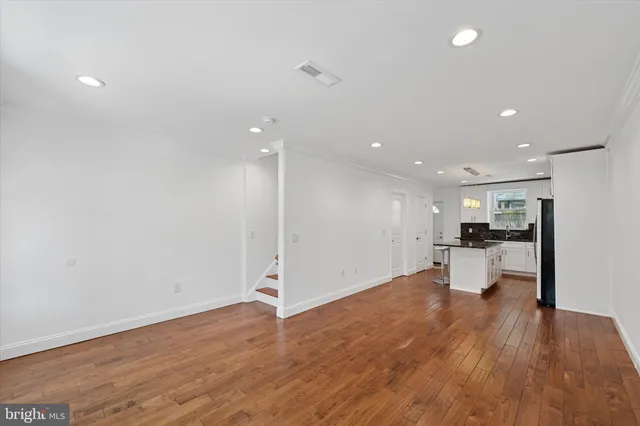 a view of an empty room and a kitchen