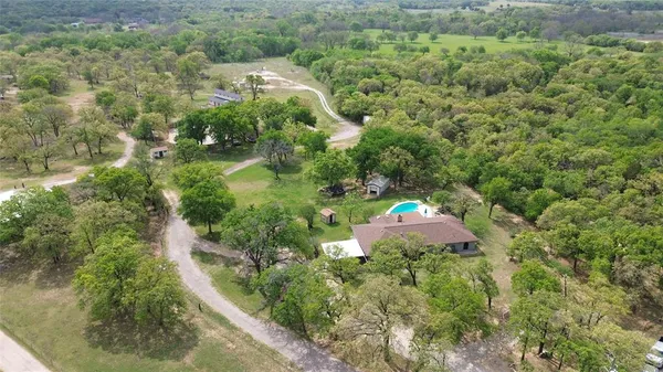 an aerial view of residential house with outdoor space and trees all around