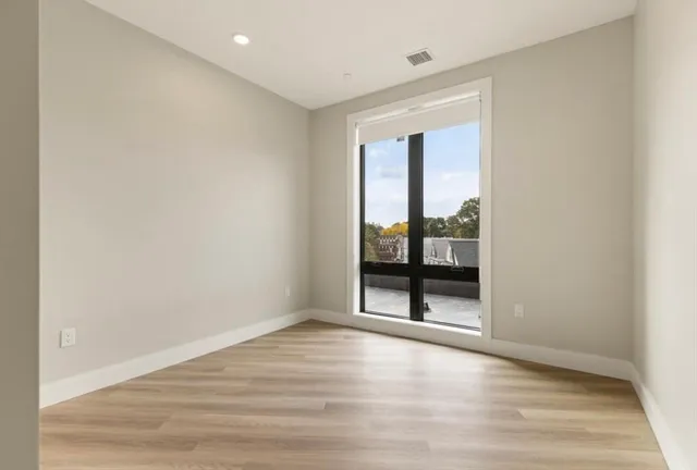 an empty room with wooden floor and windows