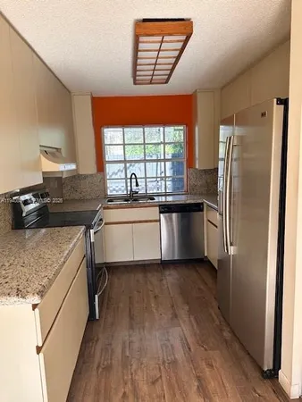 a kitchen with a sink appliances cabinets and a large window