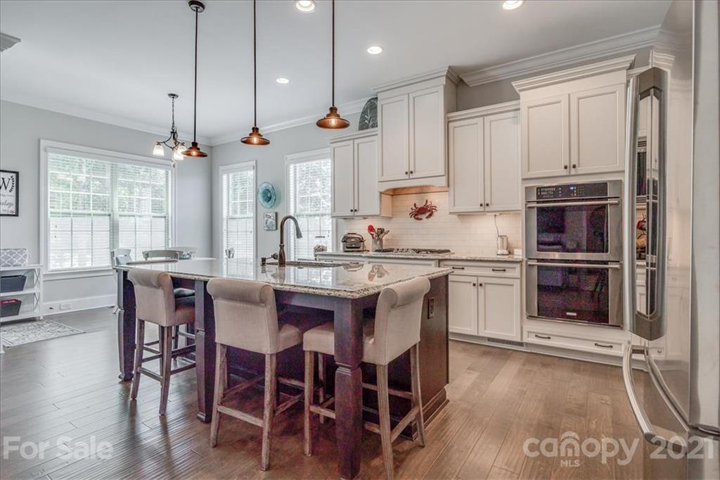 620 Zinnia Way Tega Cay, SC 29708 - Photo 12 of 39 a kitchen with kitchen island granite countertop a table chairs sink and cabinets
