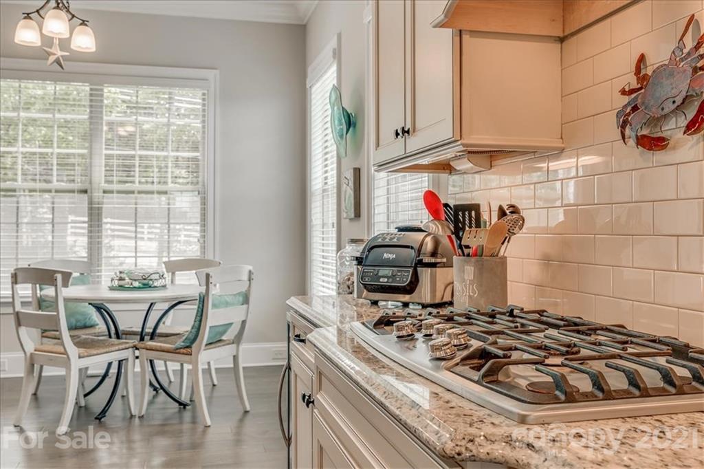 620 Zinnia Way Tega Cay, SC 29708 - Photo 15 of 39 a kitchen with kitchen island granite countertop a stove a sink and white cabinets