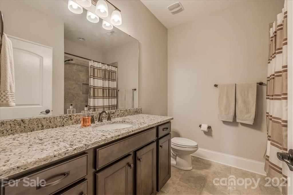 620 Zinnia Way Tega Cay, SC 29708 - Photo 28 of 39 a bathroom with a granite countertop sink a toilet and a large mirror