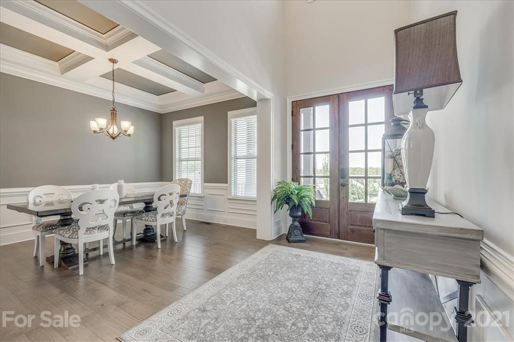 620 Zinnia Way Tega Cay, SC 29708 - Photo 7 of 39 a dining room with wooden floor a chandelier a glass table and chairs