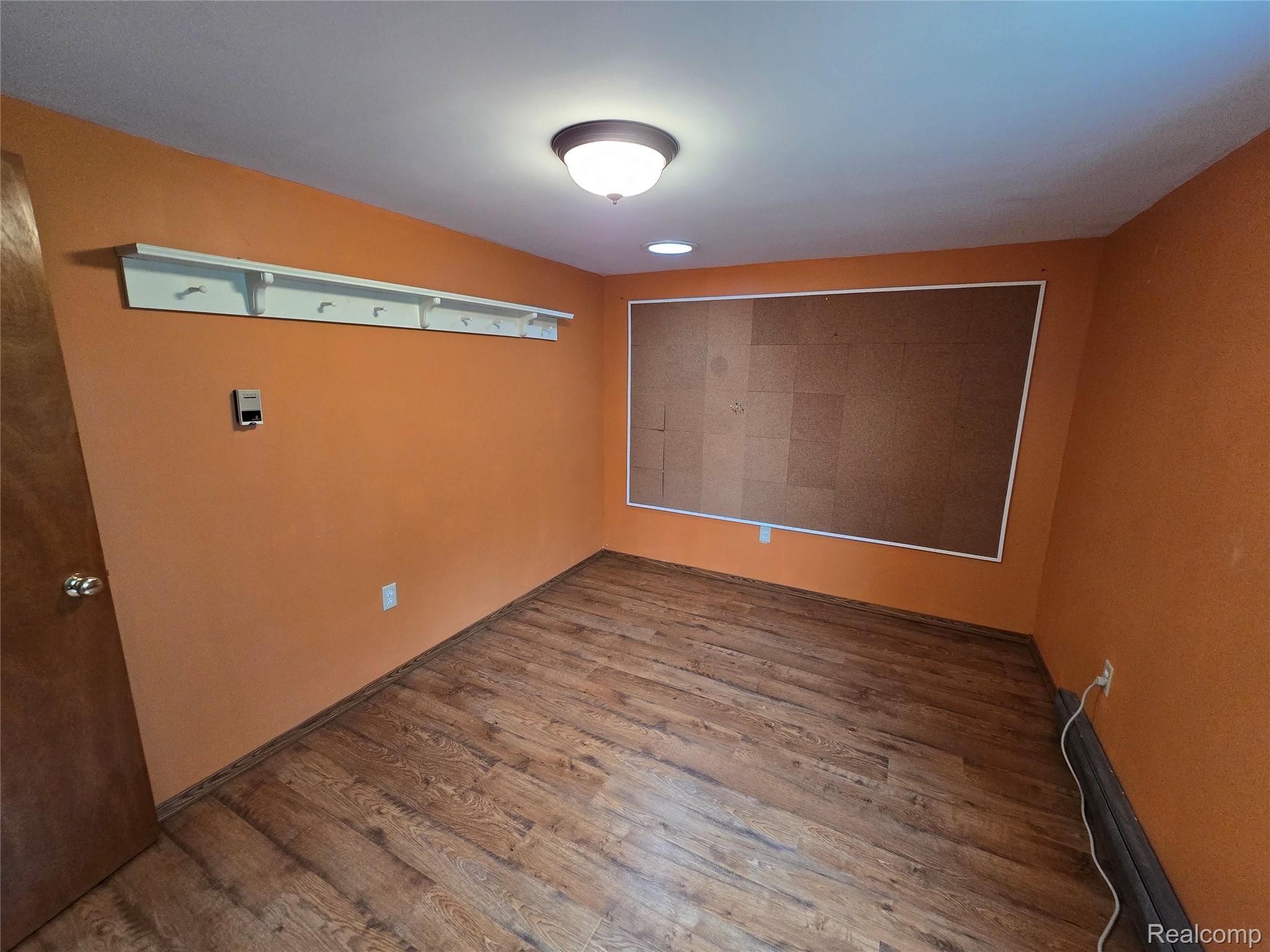 5282 McIntyre Road North Street, MI 48049 - Photo 32 of 53 Wood-finish flooring with a textured surface, a large built-in cork board, and a white coat rack with multiple hooks