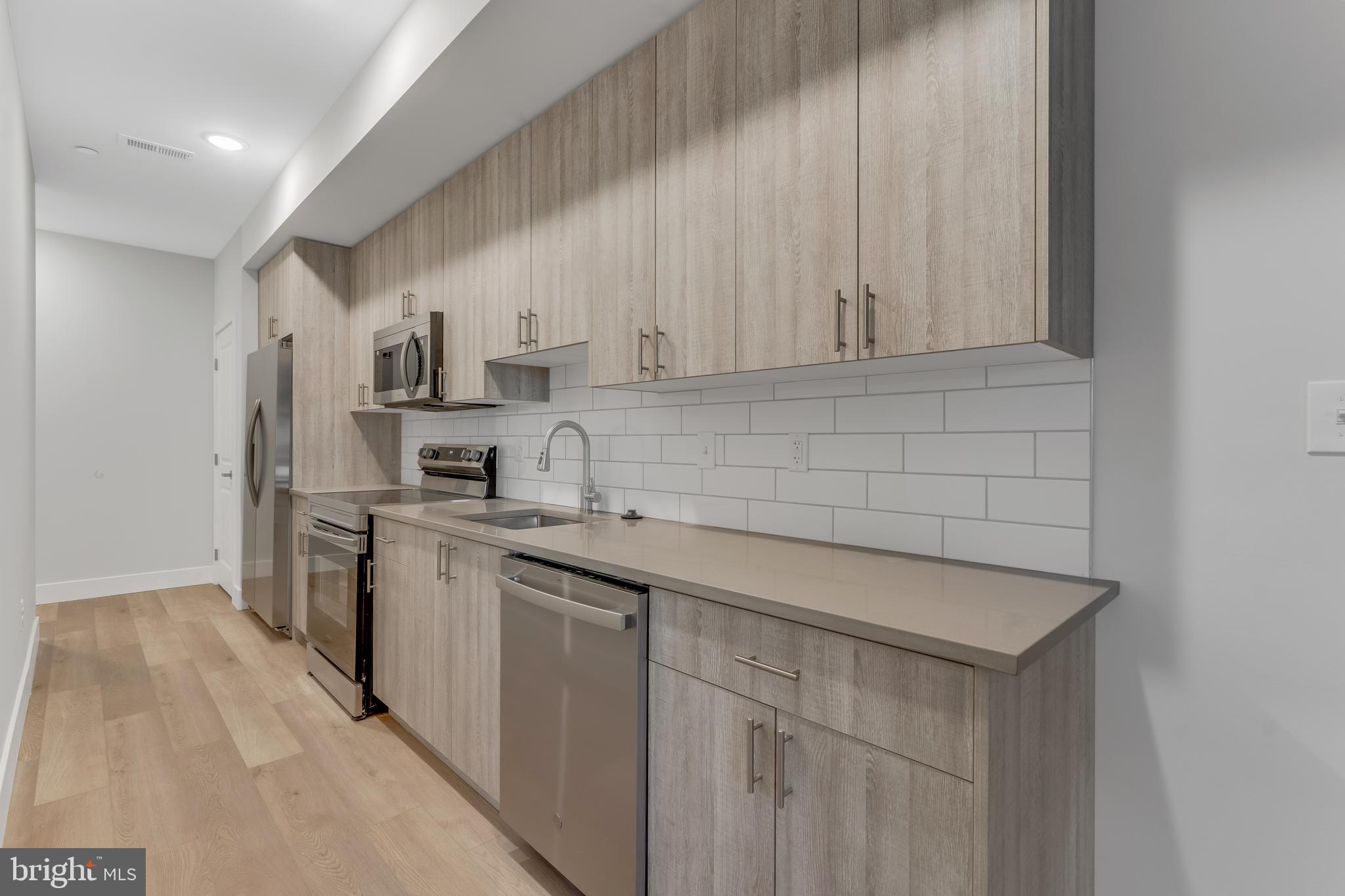 1243 West Westmoreland Street, Unit 2 Philadelphia, PA 19140 - Photo 5 of 18 a kitchen with stainless steel appliances a sink stove and cabinets
