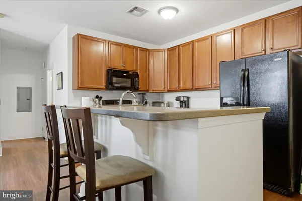 a kitchen with stainless steel appliances granite countertop a refrigerator a stove a sink a dining table and chairs with wooden floor