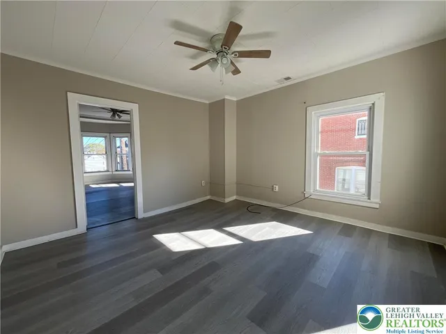 a view of an empty room with window and wooden floor