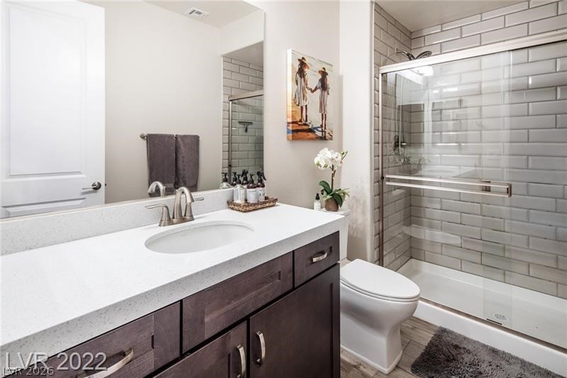 4631 Amazing View Street Las Vegas, NV 89129 - Photo 17 of 33 A well-appointed bathroom features a dark wood vanity with white countertops and a tiled walk-in shower.