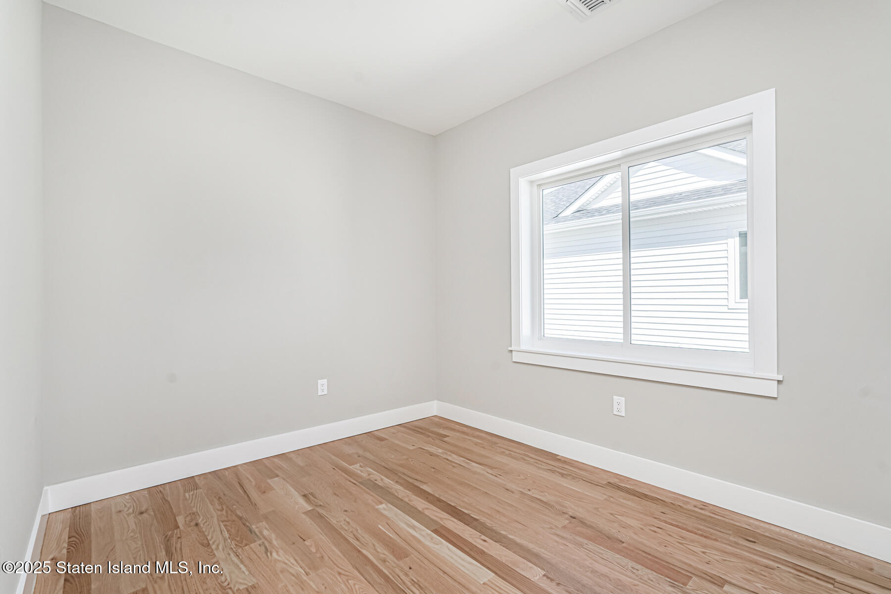 291 Rensselaer Avenue Staten Island, NY 10312 - Photo 11 of 38 an empty room with wooden floor and windows