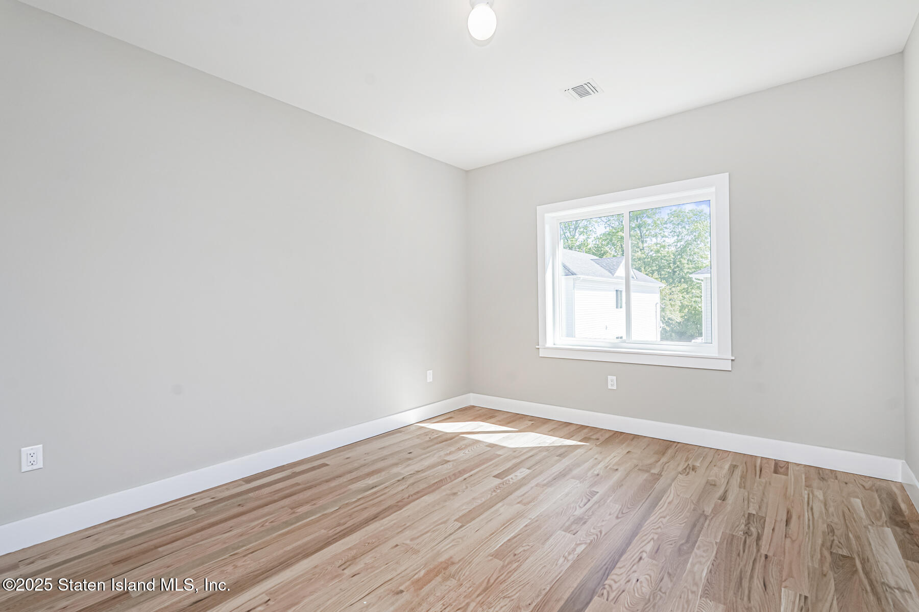 291 Rensselaer Avenue Staten Island, NY 10312 - Photo 12 of 38 an empty room with wooden floor and windows