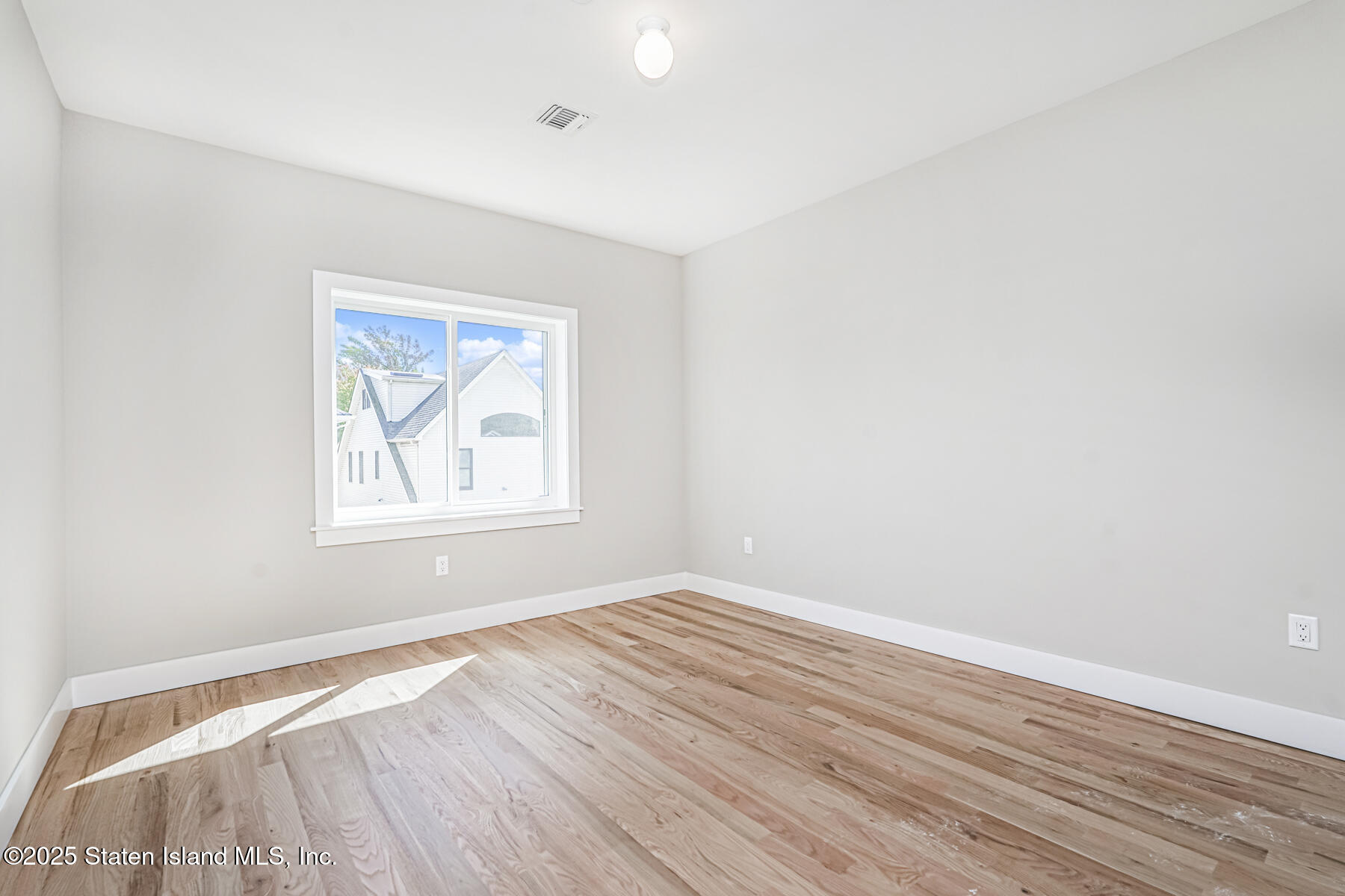 291 Rensselaer Avenue Staten Island, NY 10312 - Photo 14 of 38 an empty room with wooden floor and a window