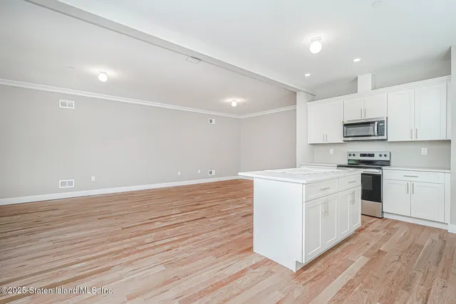 a kitchen with stainless steel appliances a white stove top oven and white cabinets