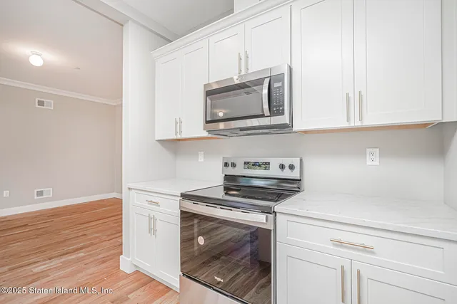 a kitchen with stainless steel appliances granite countertop white cabinets and a stove top oven