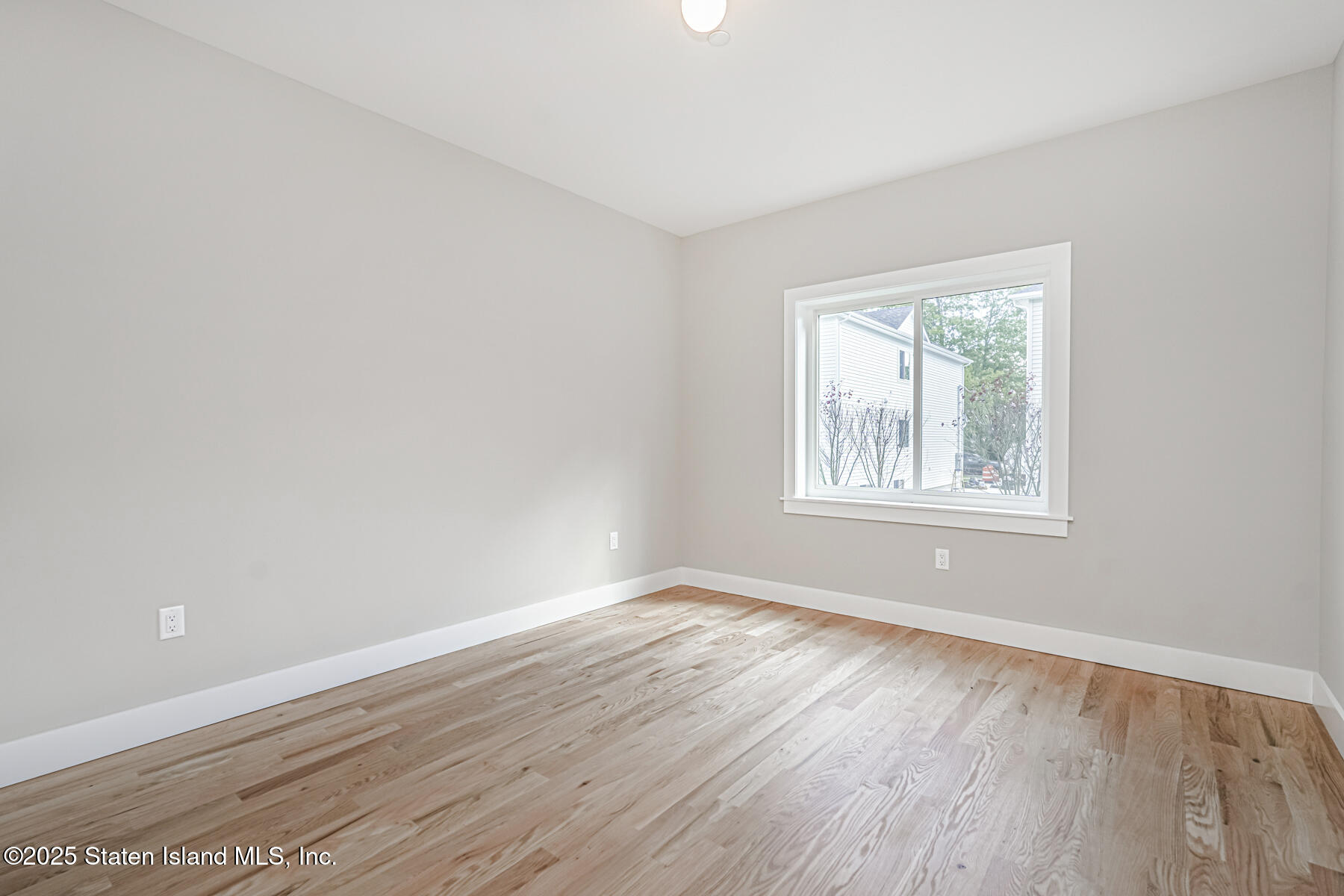 291 Rensselaer Avenue Staten Island, NY 10312 - Photo 30 of 38 a view of an empty room with wooden floor and a window