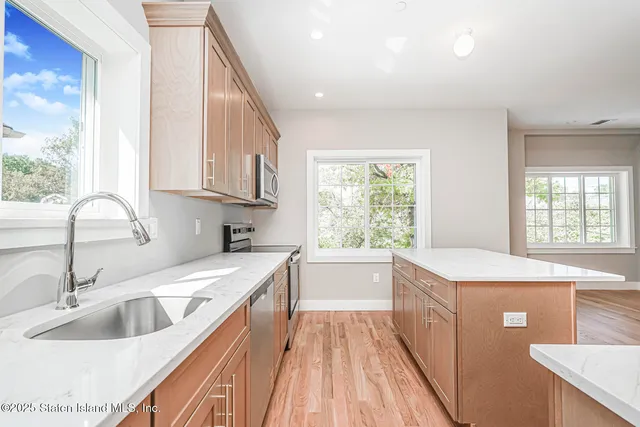 a kitchen with a sink a large window and stainless steel appliances